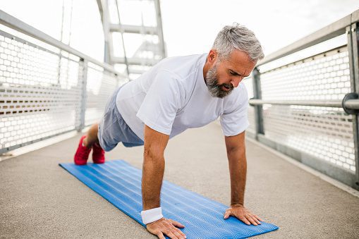 Senior sporty man doing push ups outdoors