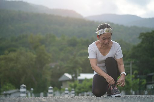 sporty-middle-aged-woman-tying-shoelace-prepare-exercise-in-the-picture-id1415724194