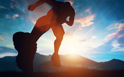 man-running-towards-the-sunset-in-the-mountains-picture-id985909812