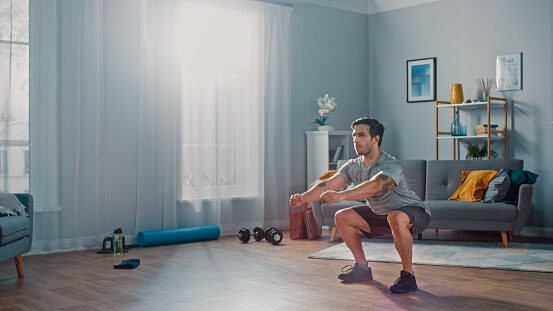 muscular-athletic-fit-man-in-tshirt-and-shorts-is-doing-squat-at-in-picture-id1172740018