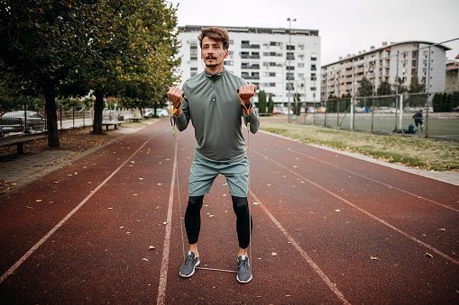 Man warms up on the athletic track with pre-workout exercises