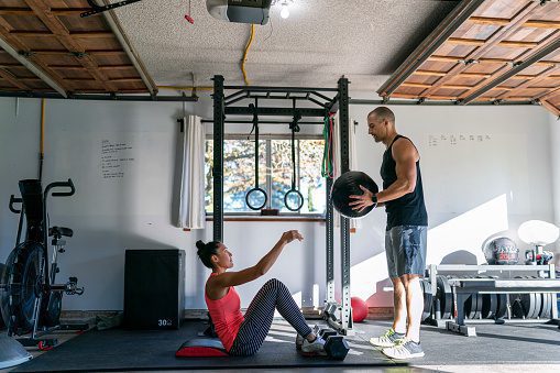 woman-exercising-with-personal-trainer-in-home-gym-picture-id1289246932